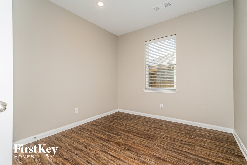 the spacious living room with hardwood flooring and a window