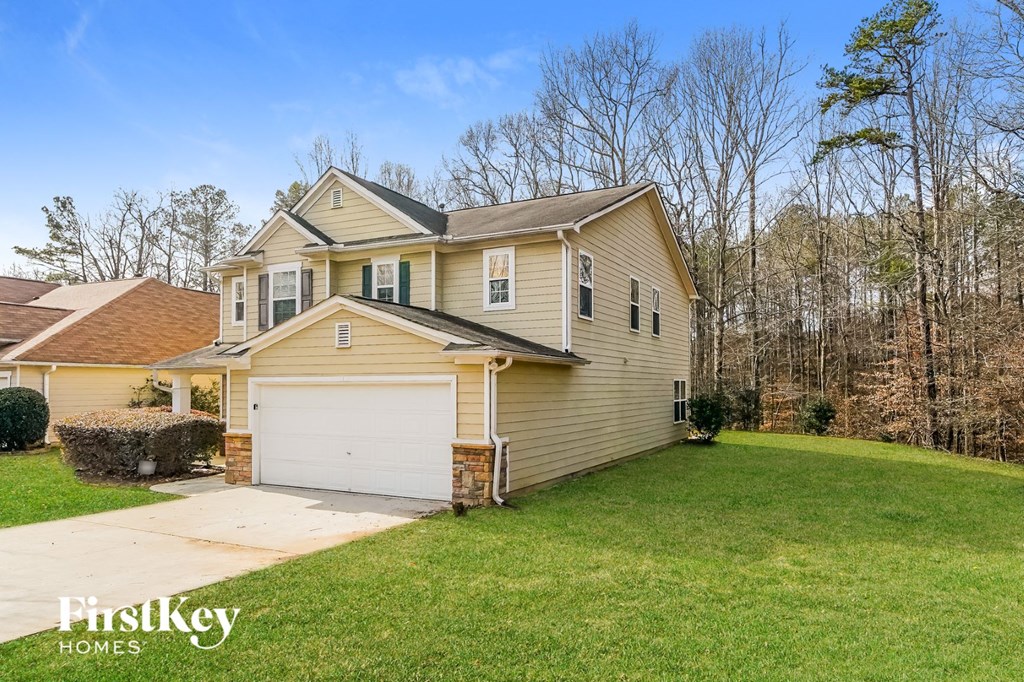 a beige house with a white garage door and a green lawn
