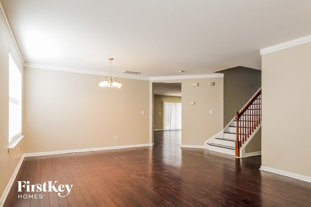 an empty living room with a staircase and wood flooring