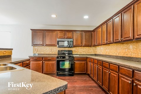 a kitchen with wood cabinets and black appliances and granite counter tops
