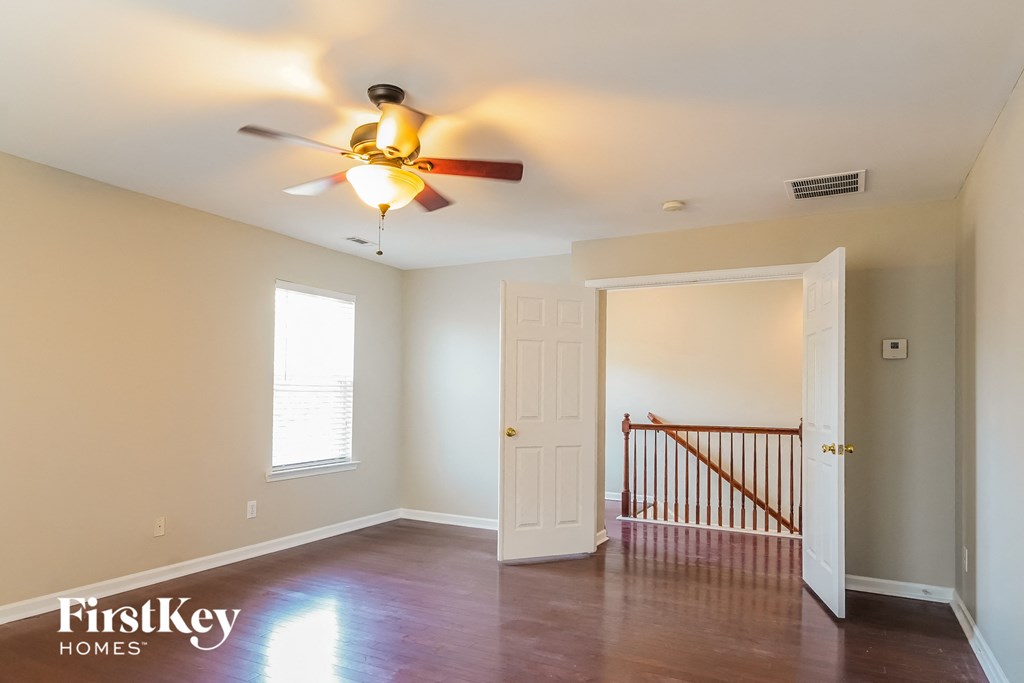 a living room with a ceiling fan and a door to a staircase