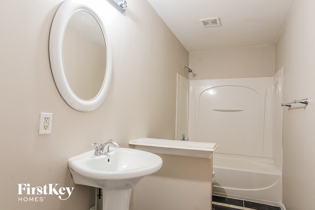 a white bathroom with a sink and a mirror and a shower