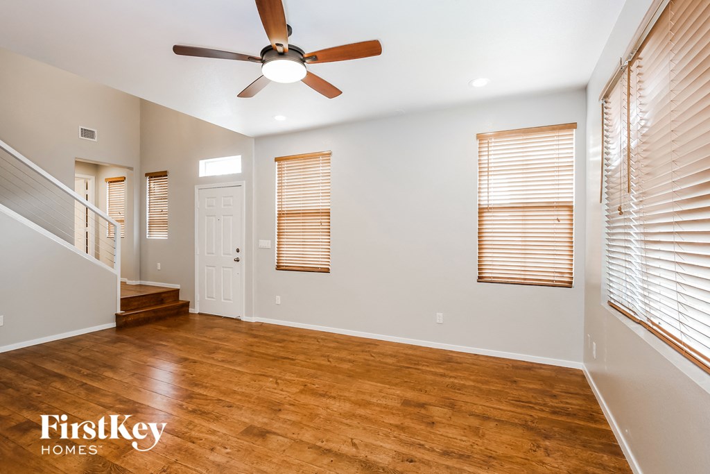 an empty living room with wood floors and a ceiling fan
