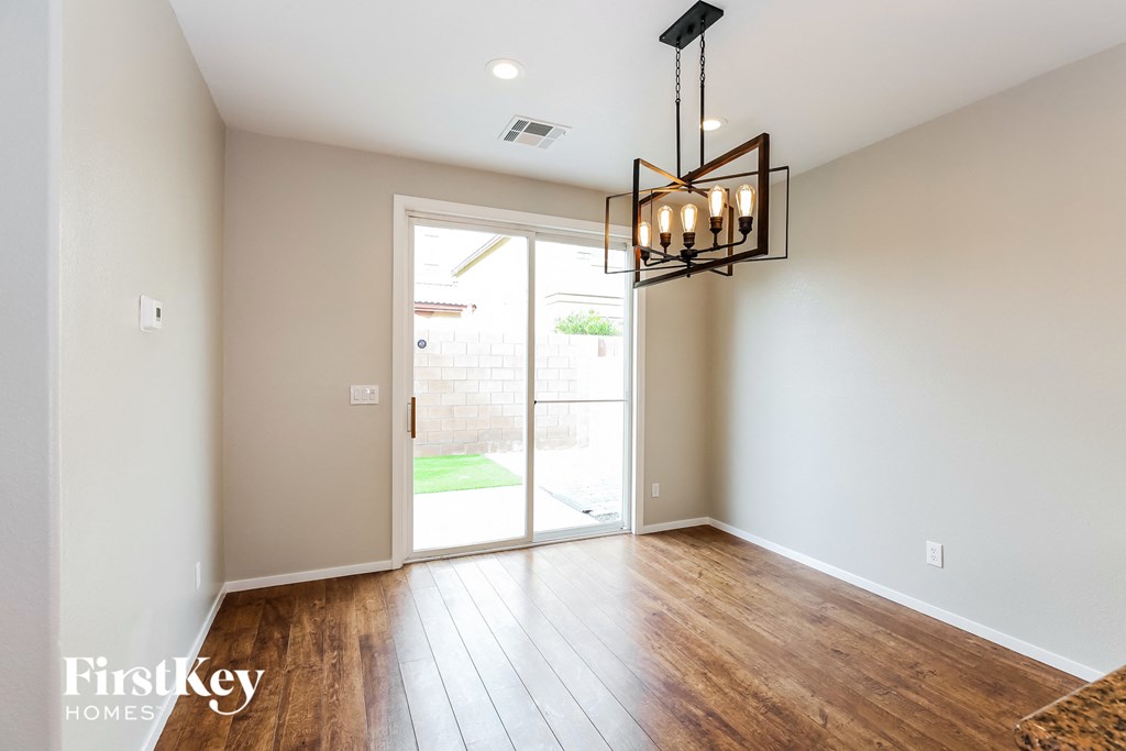 an empty living room with a door to the yard and a chandelier
