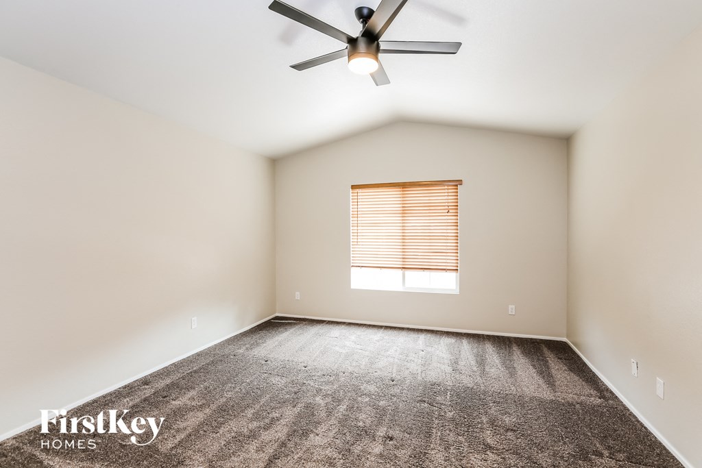 an empty room with a ceiling fan and a window
