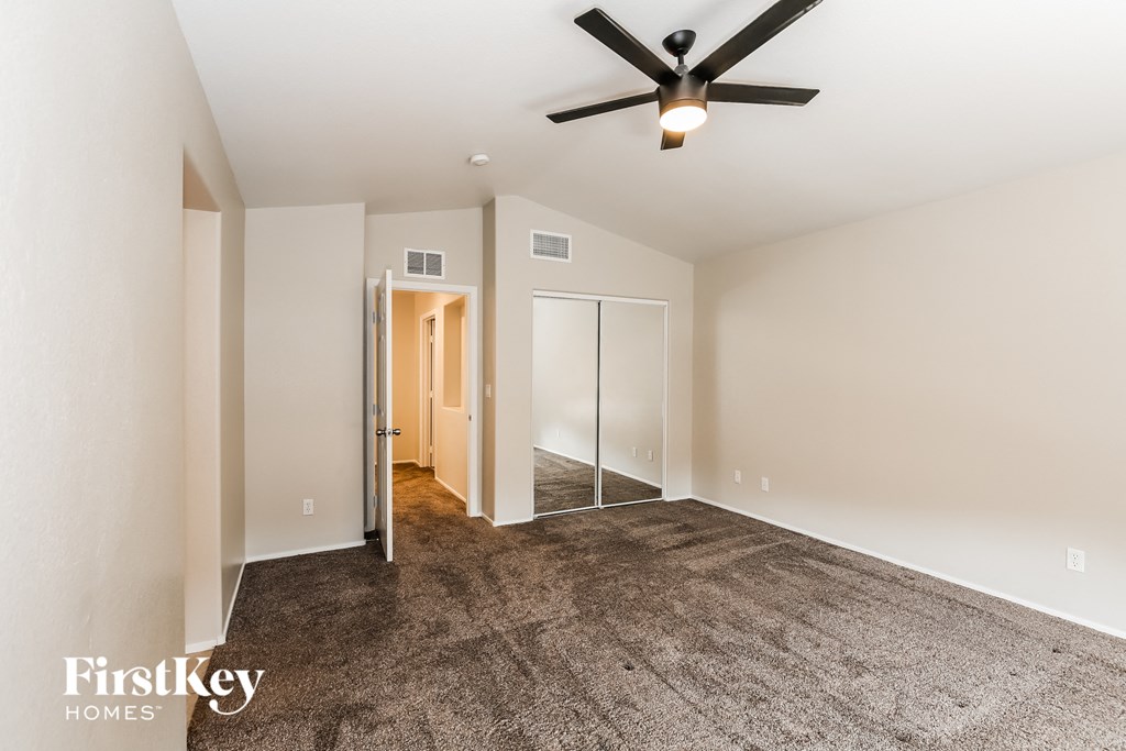 an empty living room with a ceiling fan and carpet