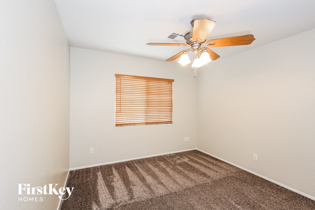 a bedroom with a ceiling fan and a carpet