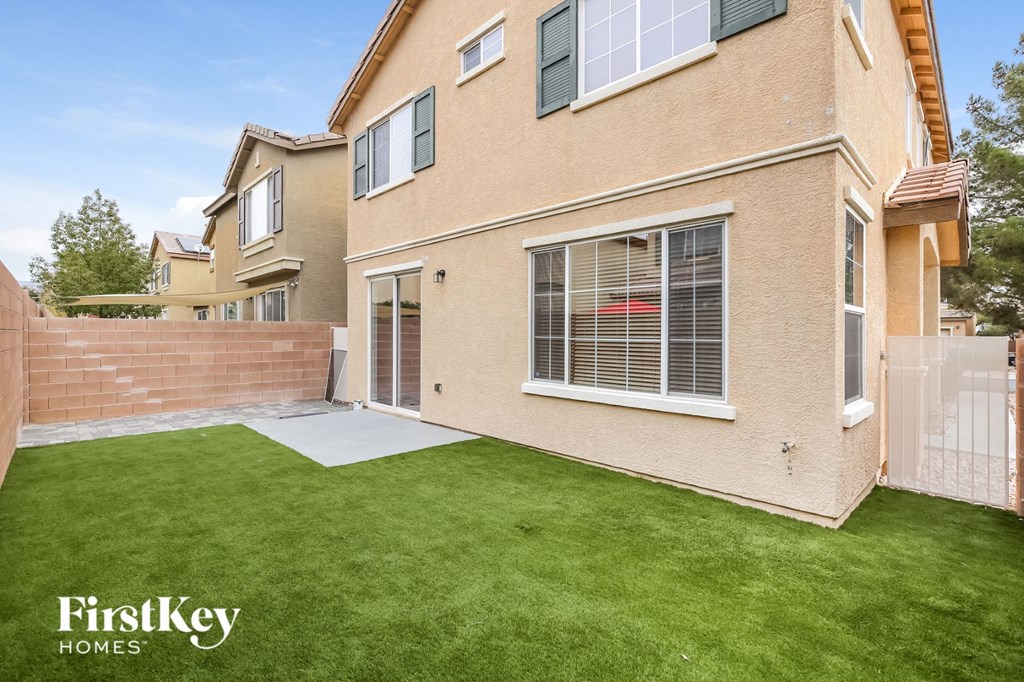 the backyard of a house with a patio and green grass