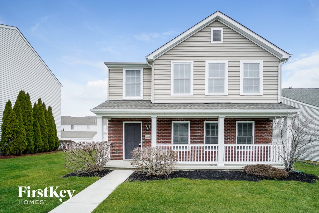 a white house with a white porch and a sidewalk in front of a green lawn