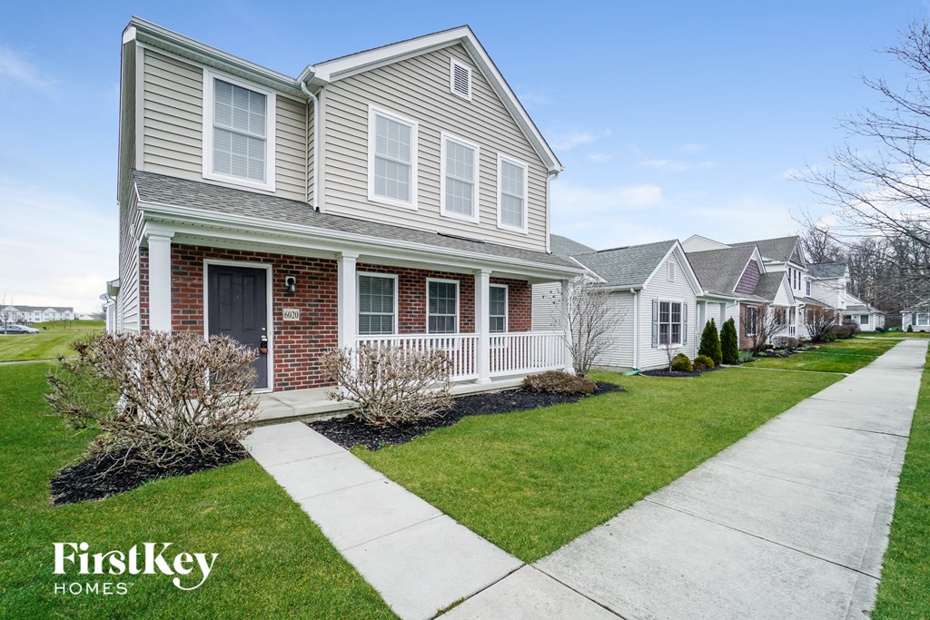 a white and brick house with a sidewalk in front of it