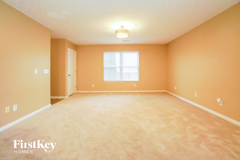 a empty living room with a large window and carpeting