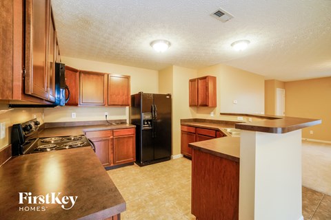 a kitchen with wooden cabinets and a black refrigerator