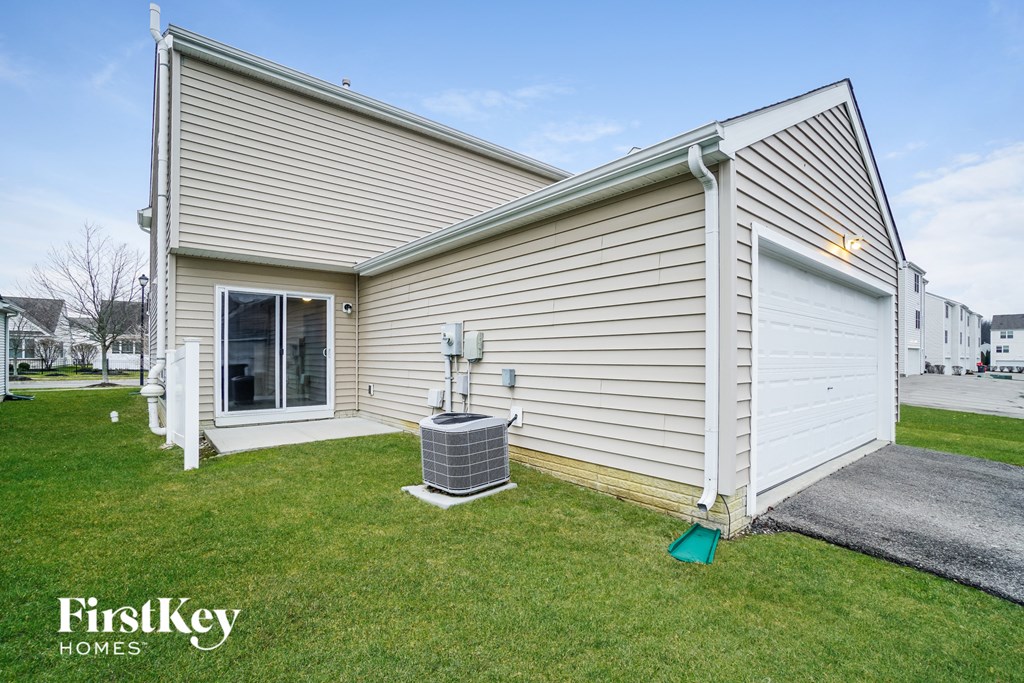 a side view of a white house with a grill on the grass