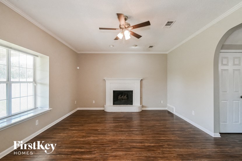 A spacious room with a fireplace and a ceiling fan.