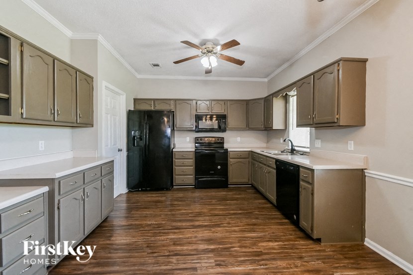 A kitchen with wooden floors and a black refrigerator.