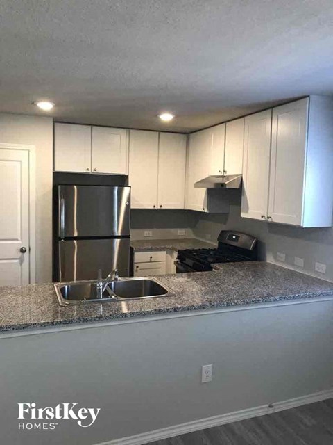 a kitchen with white cabinets and a sink and a refrigerator