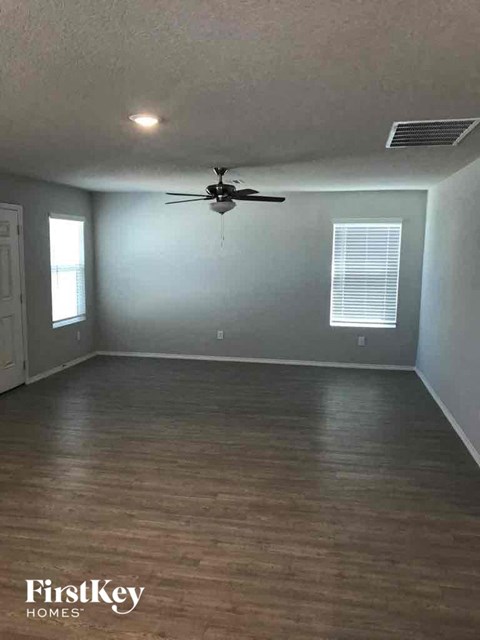 an empty living room with a ceiling fan
