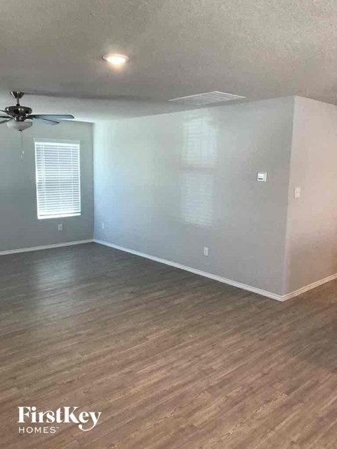 an empty living room with wood floors and a ceiling fan