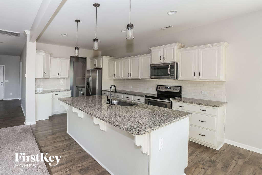 a kitchen with white cabinets and a marble counter top