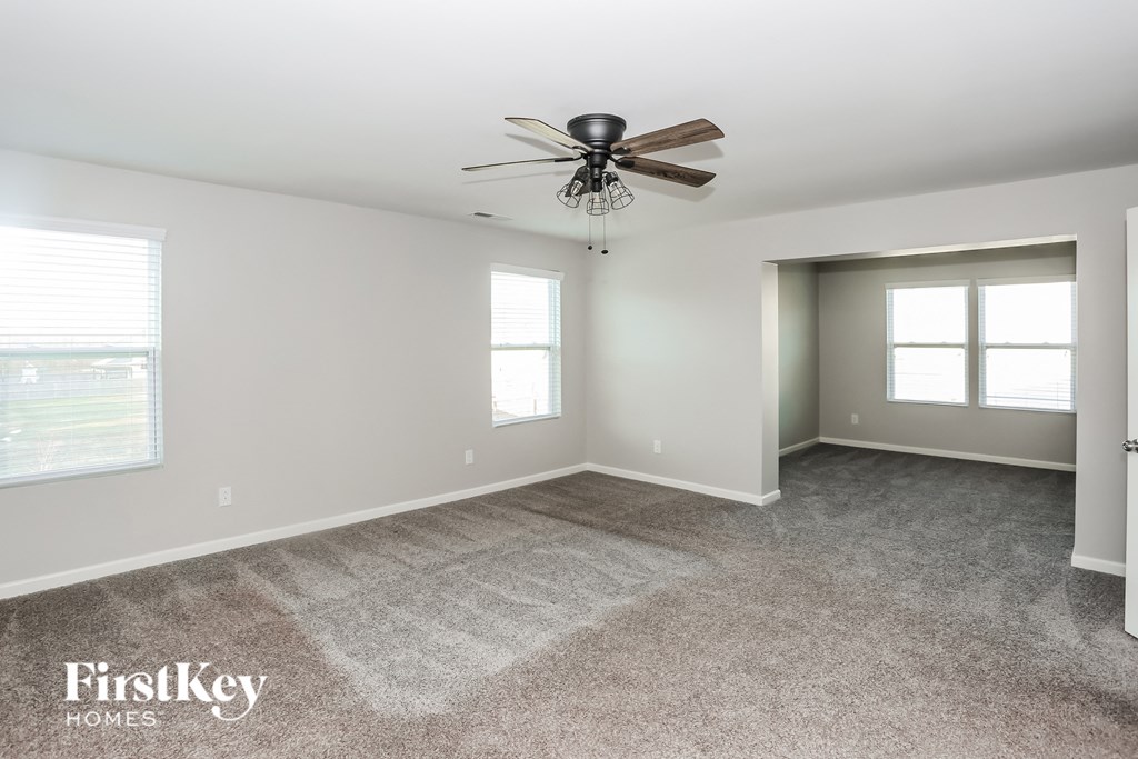 a living room with carpet and a ceiling fan