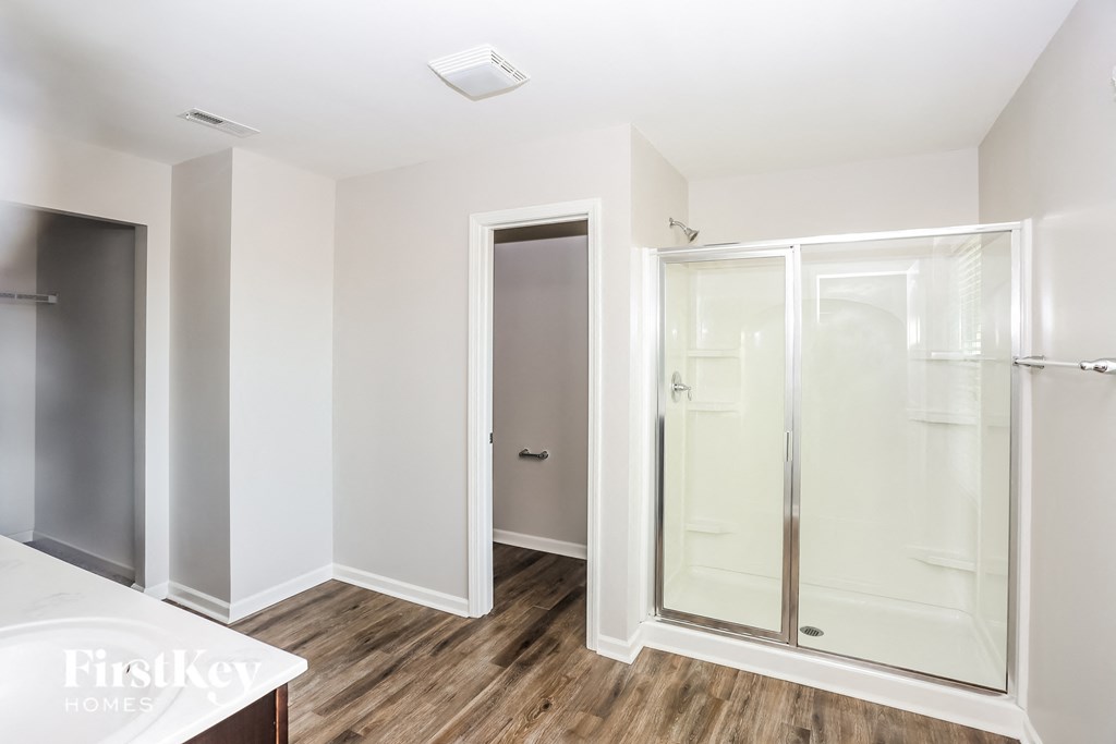 a white bathroom with a shower and a wooden floor