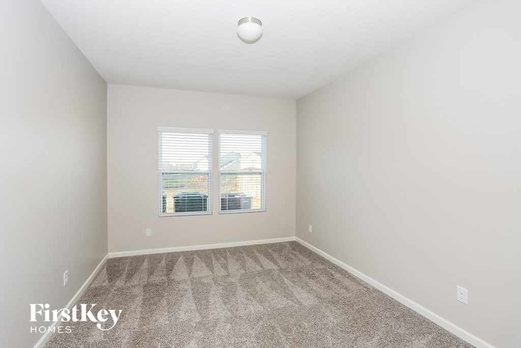 an empty room with carpet and two windows