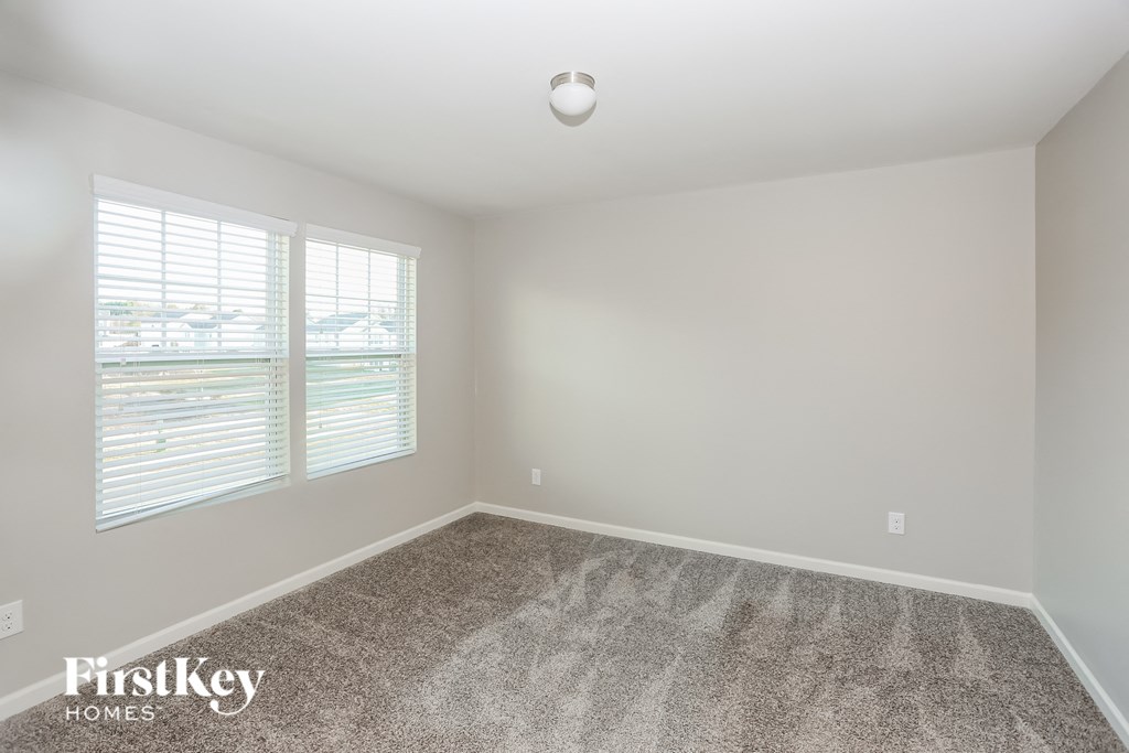 an empty room with carpet and two windows