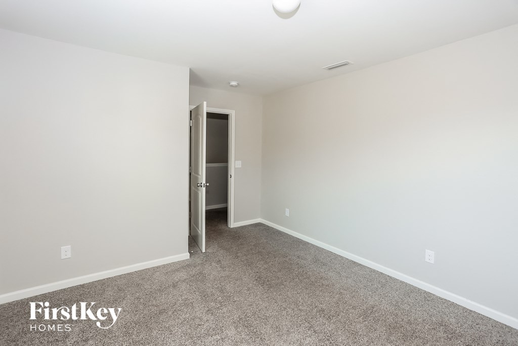 a bedroom with a carpeted floor and a door to a closet