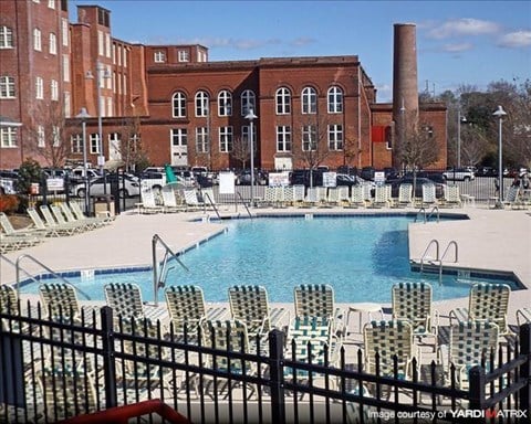 a swimming pool with chairs around it in front of a building