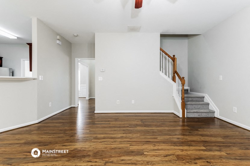 the living room and entryway of an empty house with white walls and wood floors
