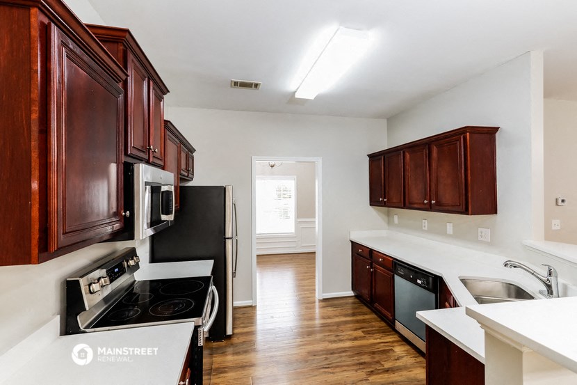a kitchen with wooden cabinets and black appliances and white counter tops
