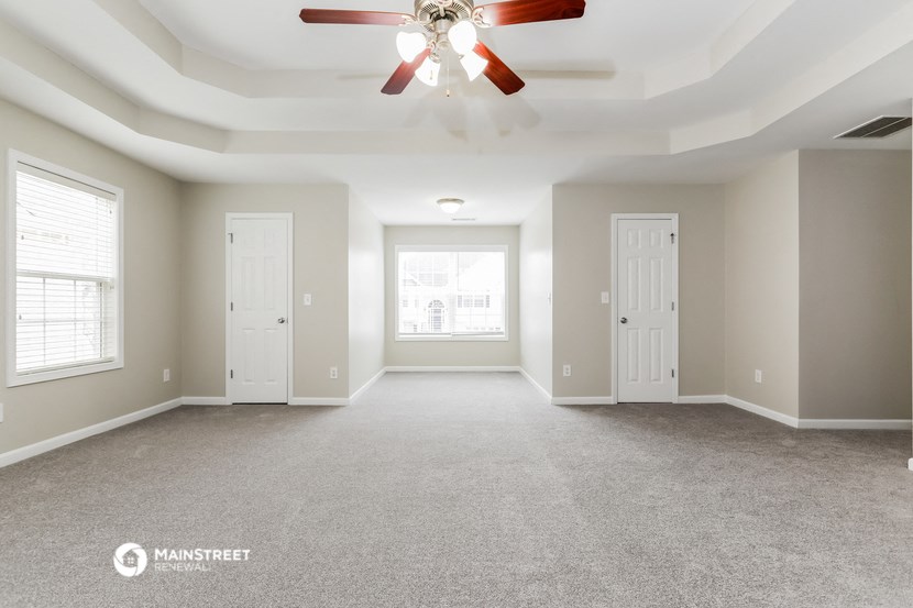 the living room of an empty home with a ceiling fan