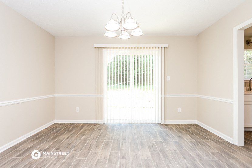 an empty living room with a large window and wood flooring