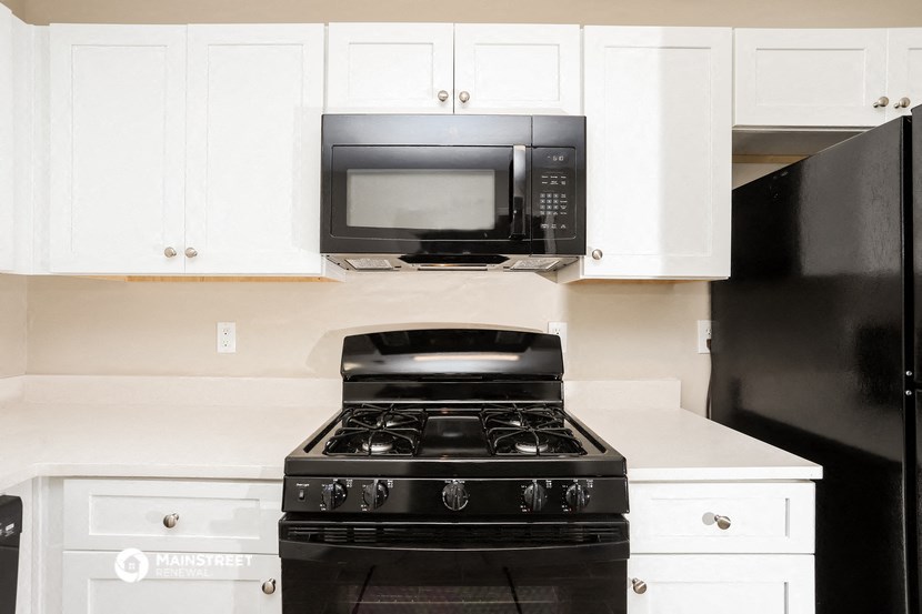 a kitchen with white cabinets and a black stove and a microwave