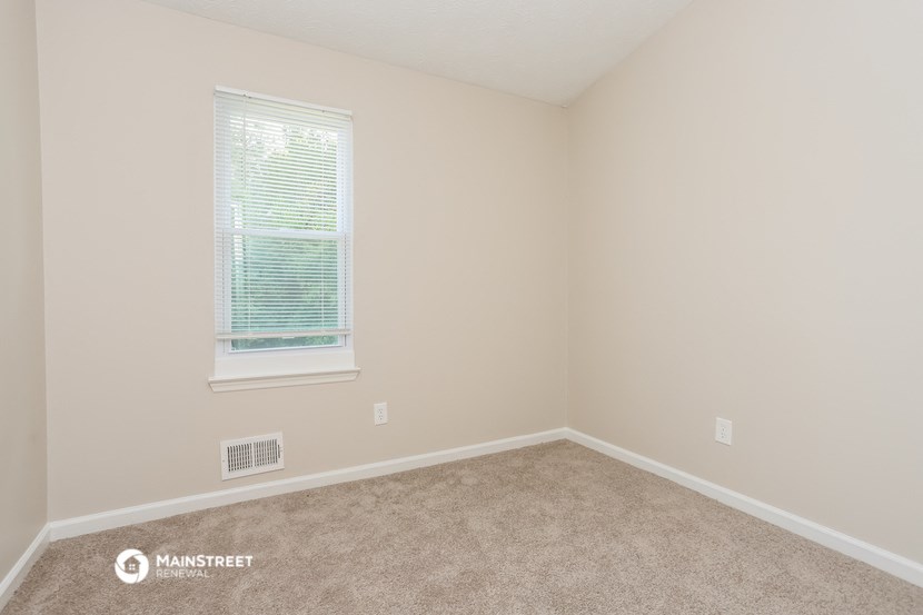 the upstairs bedroom has a carpeted floor and a window