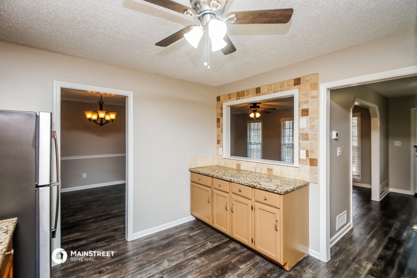 an empty kitchen with a refrigerator and a ceiling fan