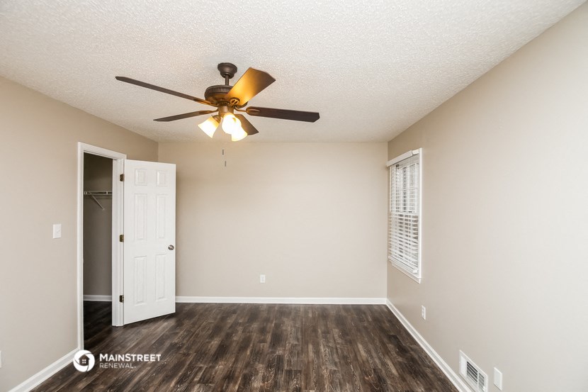 a living room with a ceiling fan and a door to a closet