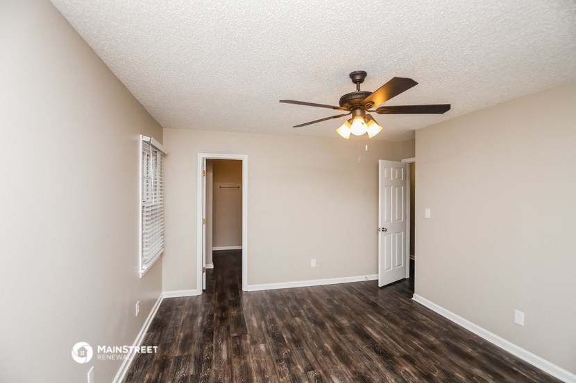 an empty living room with a ceiling fan and a door to a closet