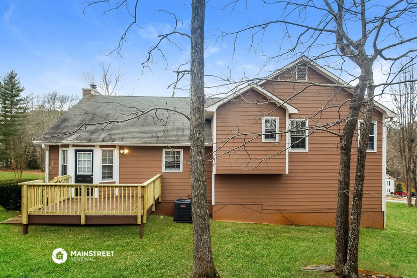 the front of a brown house with a wooden deck