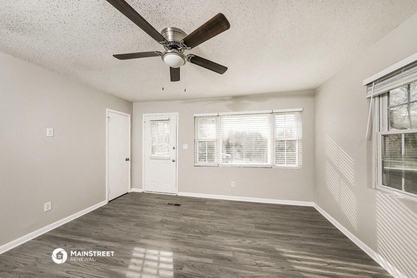 the spacious living room with ceiling fan and window