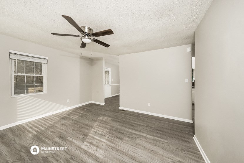 an empty living room with a ceiling fan and a window