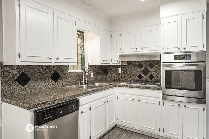 a white kitchen with granite counter tops and white cabinets