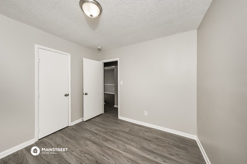 the living room of an apartment with white walls and wood flooring