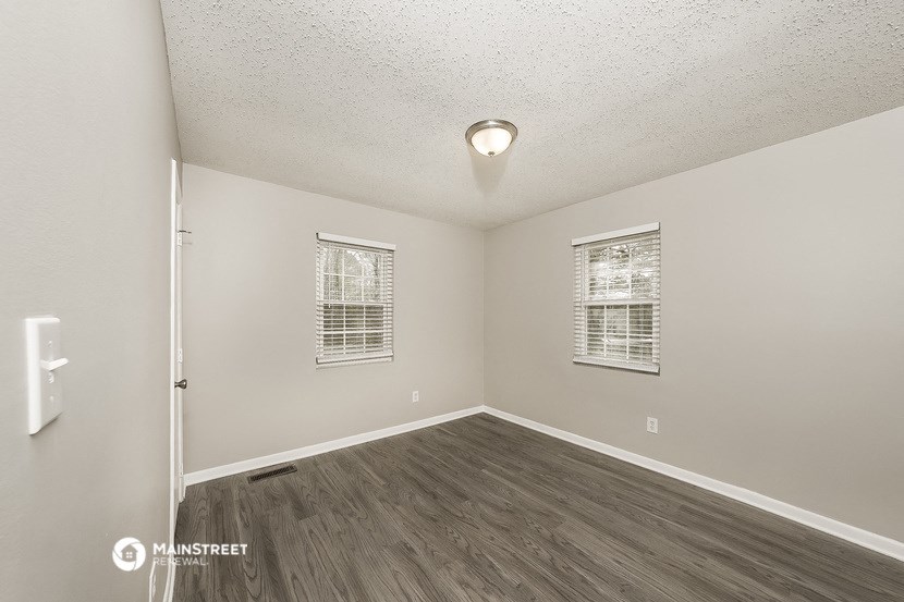 the spacious living room with hardwood flooring and two windows