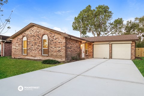 a brick house with a garage and a white driveway