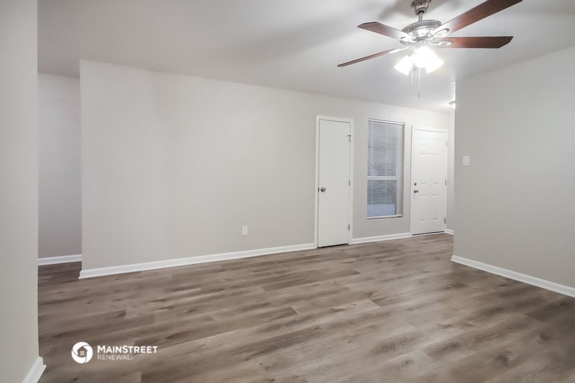 the living room of an empty apartment with a ceiling fan