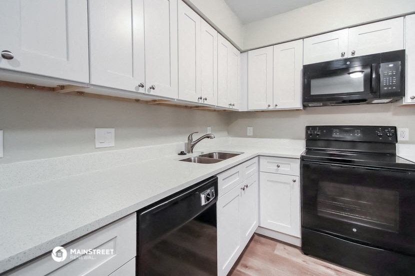 a kitchen with white cabinets and black appliances