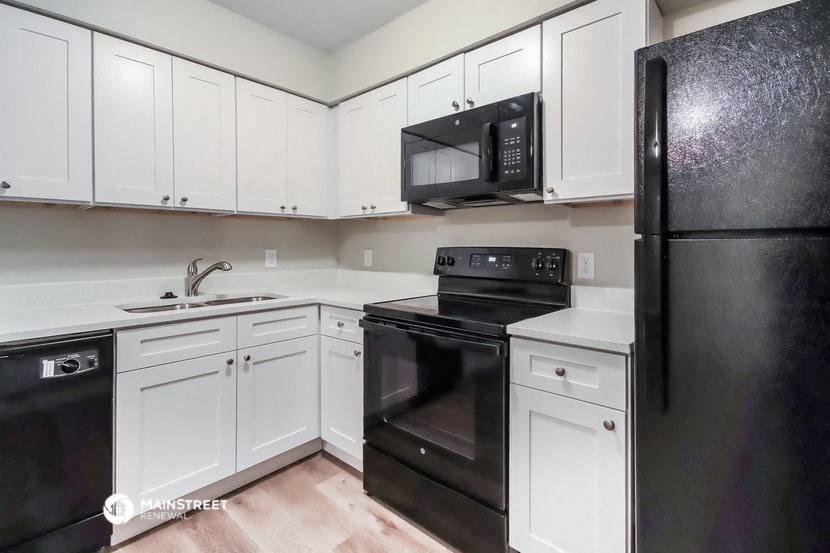 an empty kitchen with black appliances and white cabinets