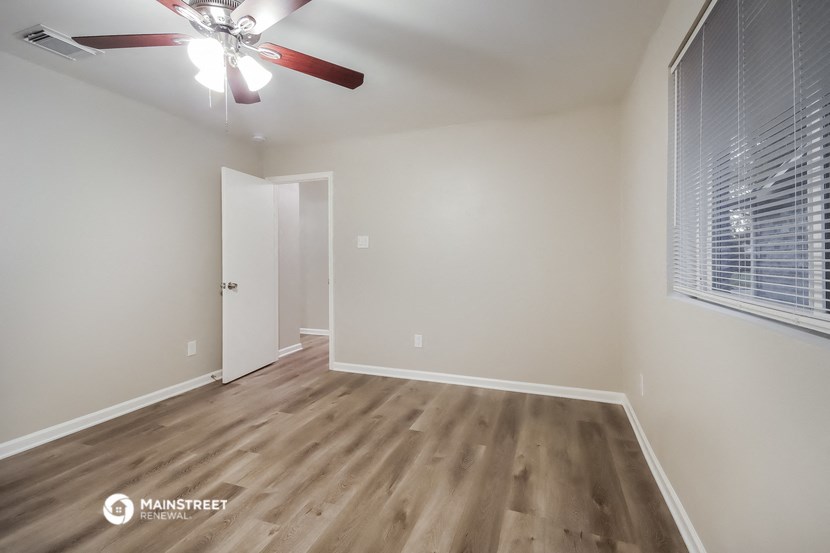 the living room of an apartment with wood flooring and a ceiling fan