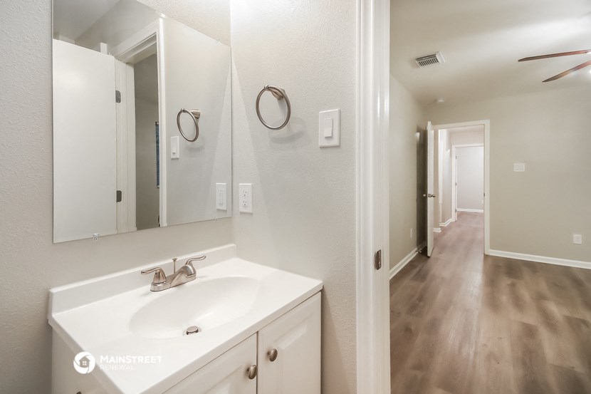 a bathroom with a sink and a mirror and a hallway